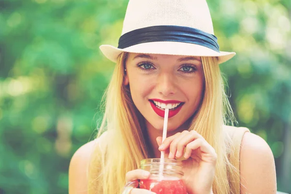 Junge Frau trinkt draußen einen Smoothie — Stockfoto
