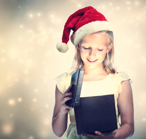 Κορίτσι με καπέλο Santa άνοιγμα συσκευασία δώρου — Φωτογραφία Αρχείου