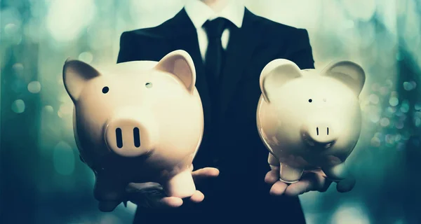 Businessman holding two piggy banks — Stock Photo, Image