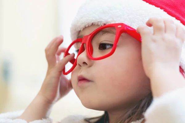Liten flicka klädd i en jultomten hatt och kostym — Stockfoto