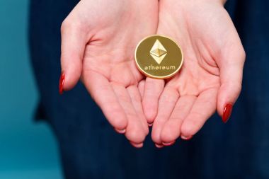 Fiziksel bir Ethereum cryptocurrency tutan kadın