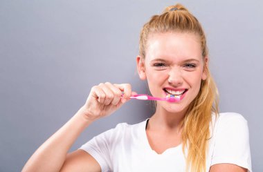 Diş fırçası tutan genç bir kadın.