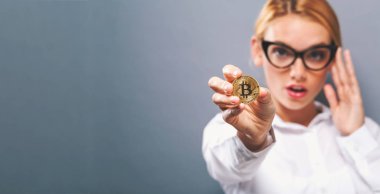 Fiziksel bir bitcoin tutan kadın