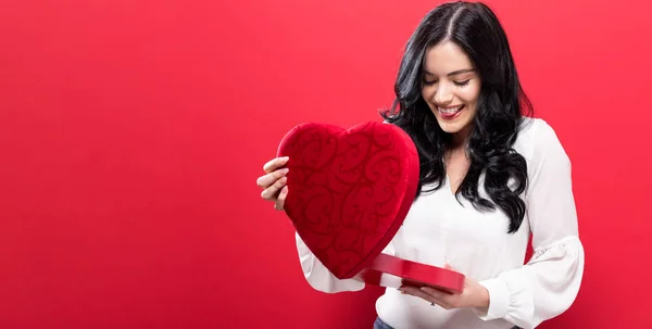 Feliz joven mujer sosteniendo una gran caja de regalo de corazón —  Fotos de Stock