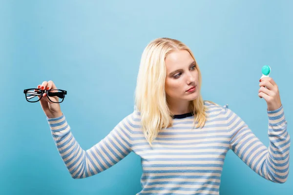 Mujer joven eligiendo entre lentes de contacto o gafas —  Fotos de Stock