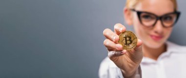 Fiziksel bir bitcoin tutan kadın
