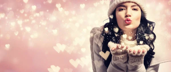 Joyeux jeune femme soufflant la neige et les cœurs — Photo