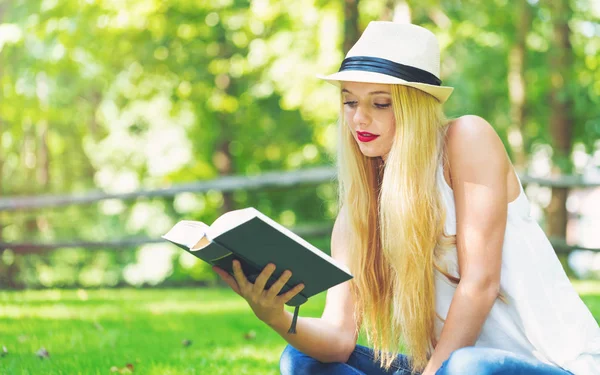 Jonge vrouw lezen van een boek buiten — Stockfoto