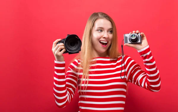 Mujer joven comparando cámaras profesionales y compactas — Foto de Stock