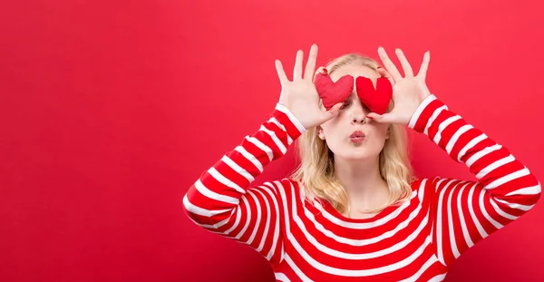 Happy young woman holding heart cushions — Stock Photo, Image