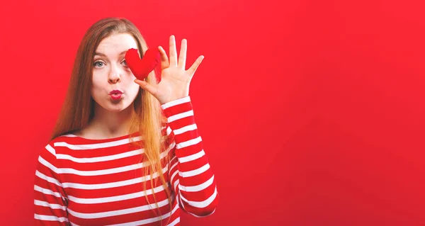 Happy young woman holding a heart cushion — Stock Photo, Image