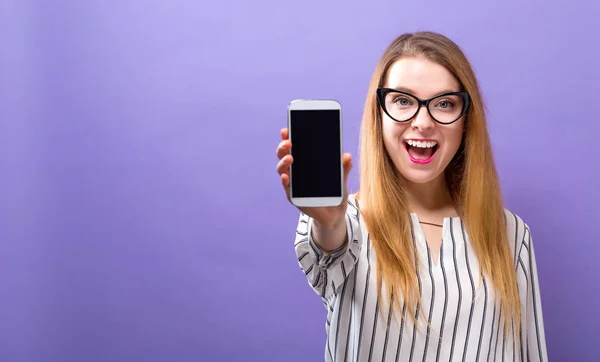 Ung kvinna håller ut en mobiltelefon — Stockfoto