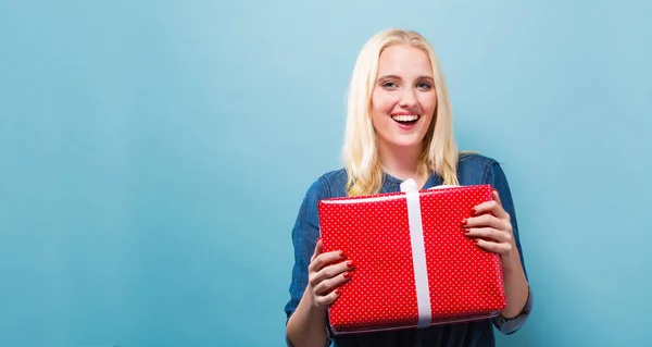 Joyeux jeune femme tenant une boîte cadeau — Photo