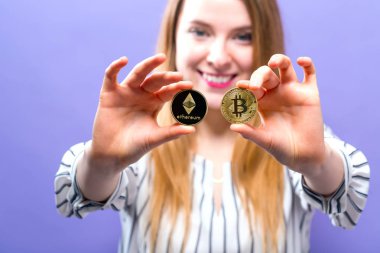 Fiziksel bitcoin ve ethereum paraları tutan kadın