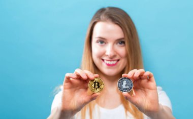 Fiziksel bitcoin ve litecoin tutan kadın