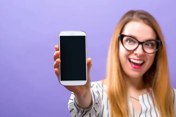 Ung kvinna håller ut en mobiltelefon — Stockfoto