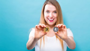 Fiziksel bitcoin ve litecoin tutan kadın