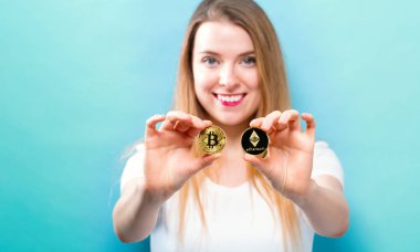 Fiziksel bitcoin ve ethereum paraları tutan kadın