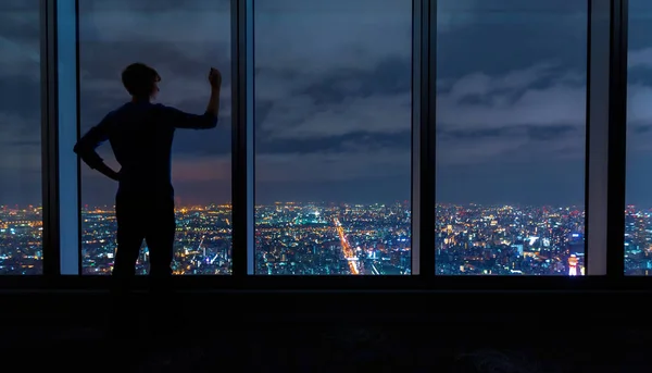 Muž píše velkými okny vysoko nad rozléhající se město — Stock fotografie