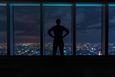 Büyük pencereler üzerinde yayılan bir şehir yüksek bakarak adam