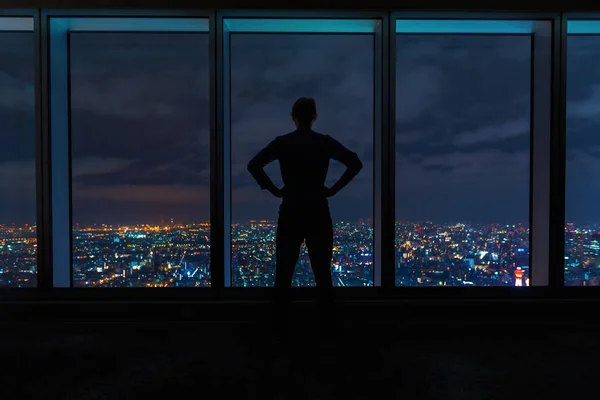 Hombre mirando por grandes ventanas por encima de una ciudad en expansión — Foto de Stock