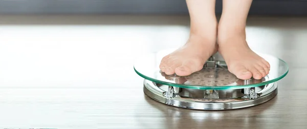 Feet of a young woman measuring her weight on a scale — Stock Photo, Image