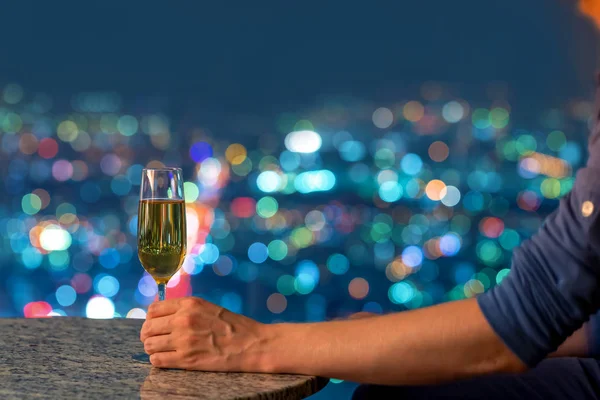 Man with wine high above the city at night