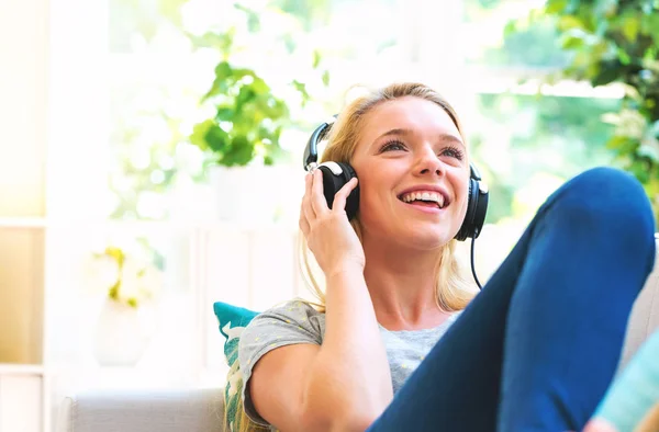 Šťastná mladá žena poslouchá hudbu na sluchátkách — Stock fotografie