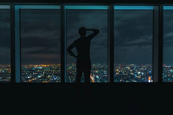 Hombre mirando por grandes ventanas por encima de una ciudad en expansión — Foto de Stock