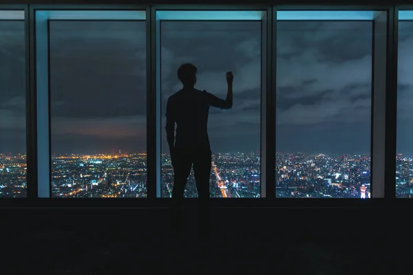 Ο άνθρωπος που γράφει σχετικά με μεγάλα παράθυρα και ψηλά πάνω από μια αχανή πόλη — Φωτογραφία Αρχείου