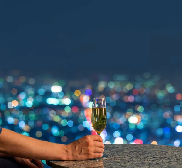 Mannen med vin högt ovanför staden på natten — Stockfoto