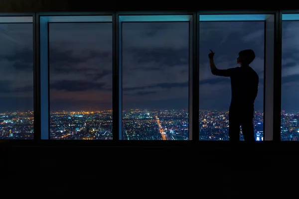 Hombre mirando por grandes ventanas por encima de una ciudad en expansión — Foto de Stock