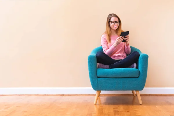 Молодая женщина читает с электронным читателем в большой комнате — стоковое фото