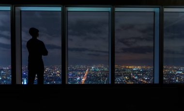 Büyük pencereler üzerinde yayılan bir şehir yüksek bakarak adam