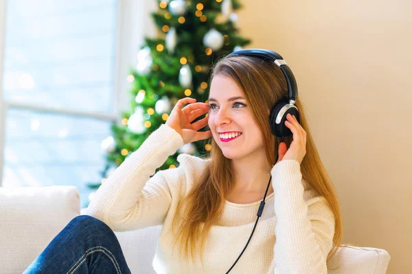 Šťastná mladá žena poslouchá hudbu na sluchátkách — Stock fotografie
