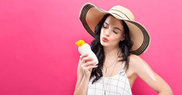 Giovane donna con in mano una bottiglia di crema solare — Foto Stock