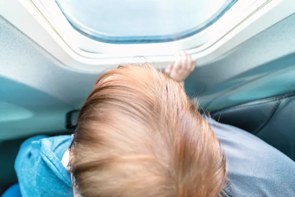Bambino ragazzo guardando fuori dalla finestra di un aereo — Foto Stock