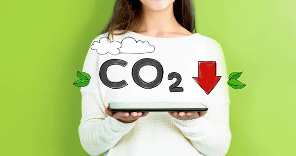 Réduire le CO2 avec une femme tenant un comprimé — Photo