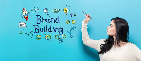 Brand Building dengan wanita muda memegang pena — Stok Foto