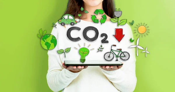 Réduire le CO2 avec une femme tenant un comprimé — Photo
