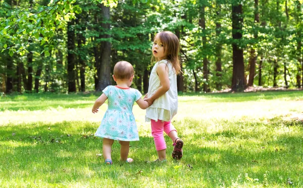 外の手を繋いでいる 2 人の若い姉妹 — ストック写真