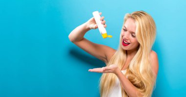 Güneş kremi bir şişe tutan genç kadın