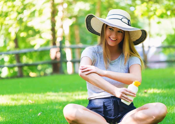 Junge Frau eine Flasche Sonnencreme draußen — Stockfoto