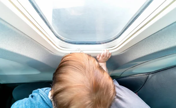 Bambino ragazzo guardando fuori dalla finestra di un aereo — Foto Stock