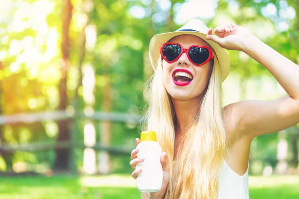 Giovane donna con crema solare e occhiali da sole — Foto Stock
