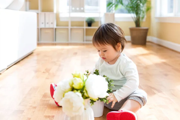 Glada barnet pojke leker med blommor — Stockfoto