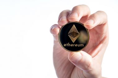 Beyaz bir arka plan üzerinde bir eter Ethereum para tutan adam