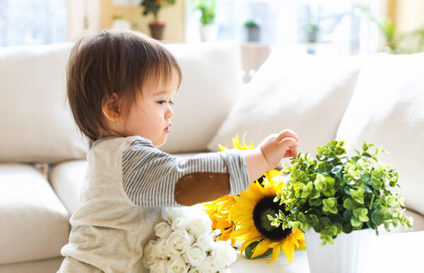 Happy toddler boy playing with flowers