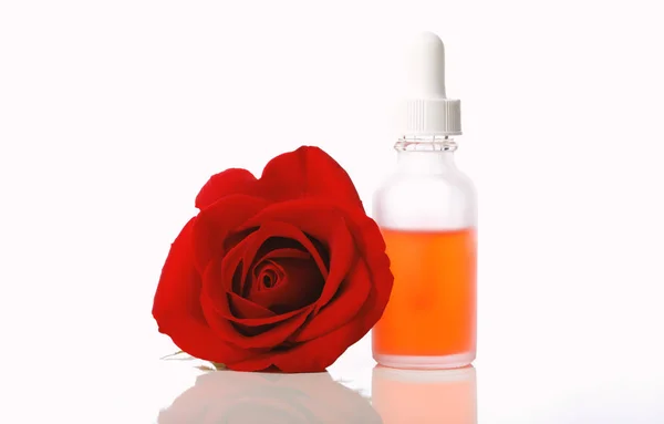 Butelka z kroplomierzem z róży kwiat na białym tle — Zdjęcie stockowe