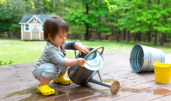 Toddler boy playing with a watering can — Stock Photo, Image